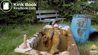 Busty babe masturbating in a bathtub full with cow shit