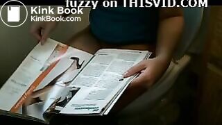 Attractive brunette reading while taking a shit